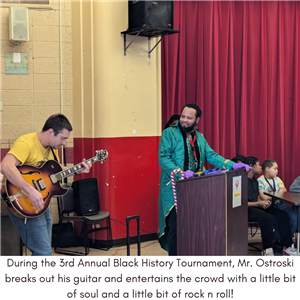 Mr Ostrowski playing his guitar as Mr Watkins looks on.
